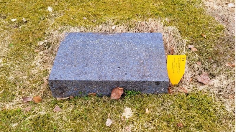 Bilde av nedlagt gravstein med gult merke