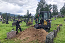 Kirkegårdsarbeidere med gravemaskin, gjør klar grav til gravferd. Foto: Anders Nyhuus