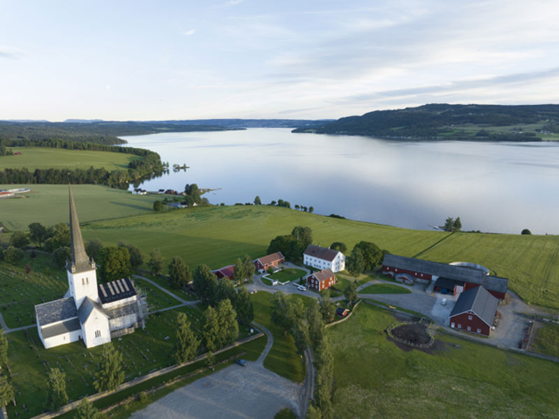 Ringsaker kirke og prestegård ligger vakkert til langs Mjøsa. Foto: OVF