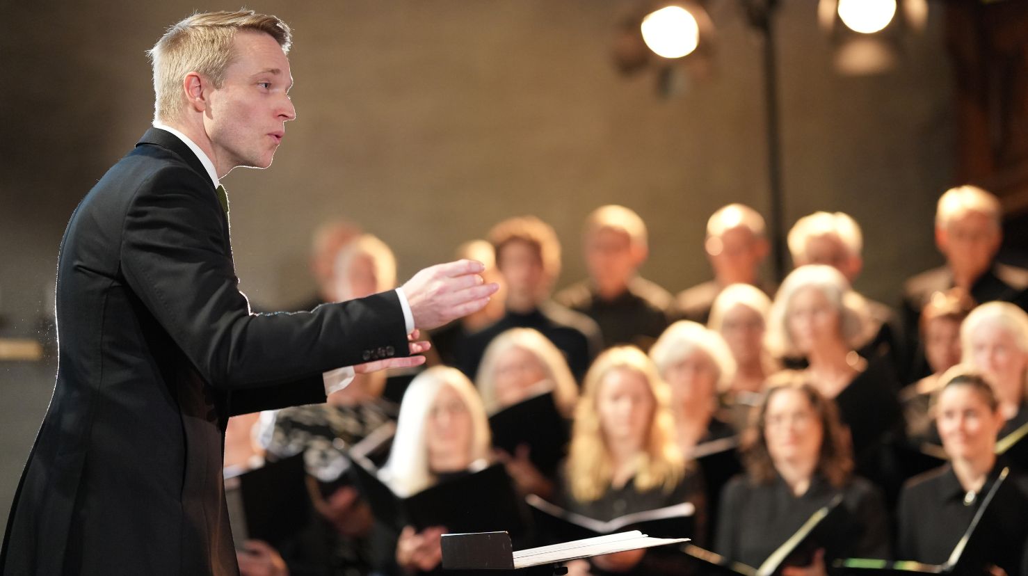 Mannlig dirigent under kirkekonsert. Foto.