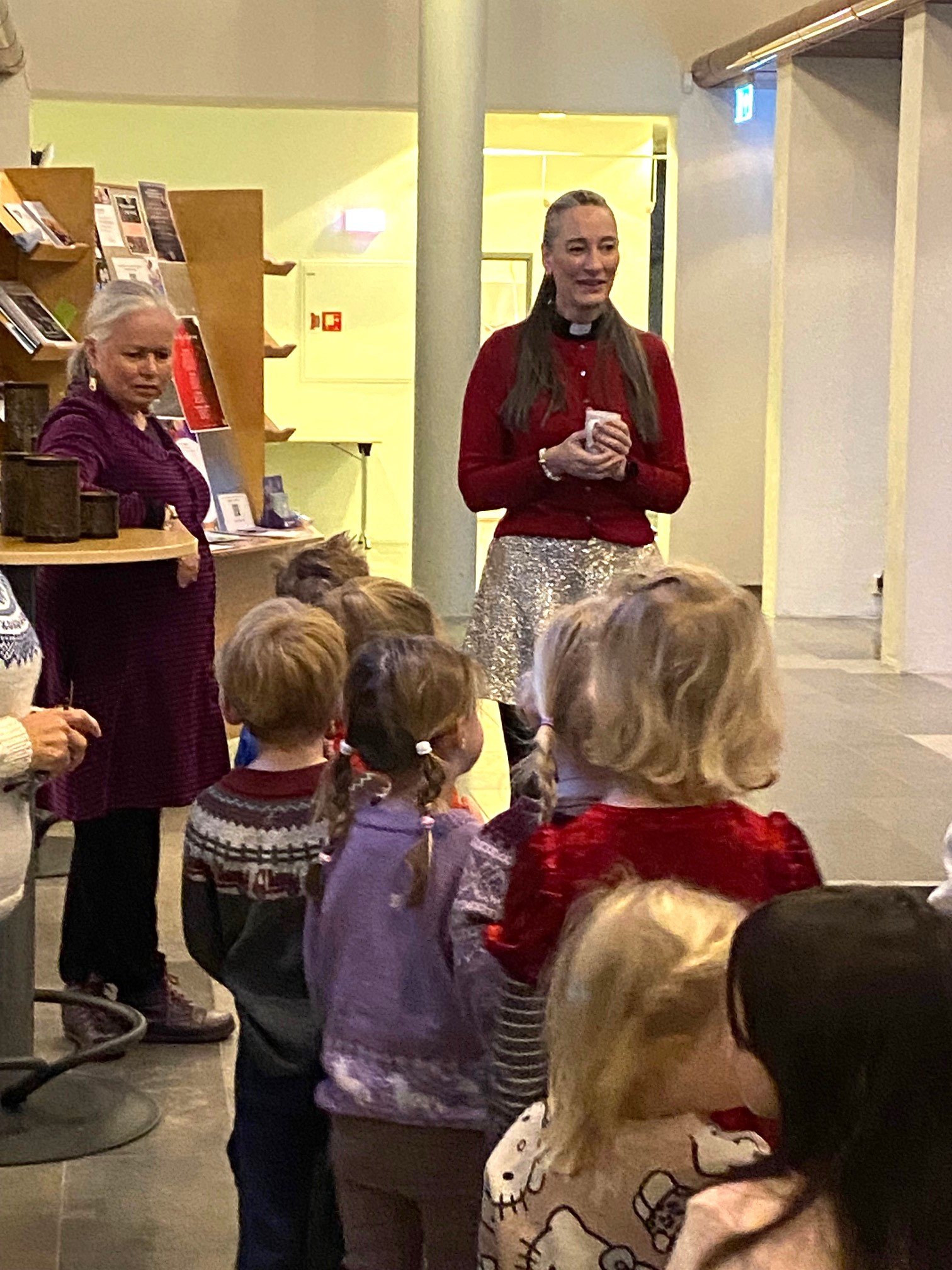 Prest og pedagog står framfor barn og snakker med de